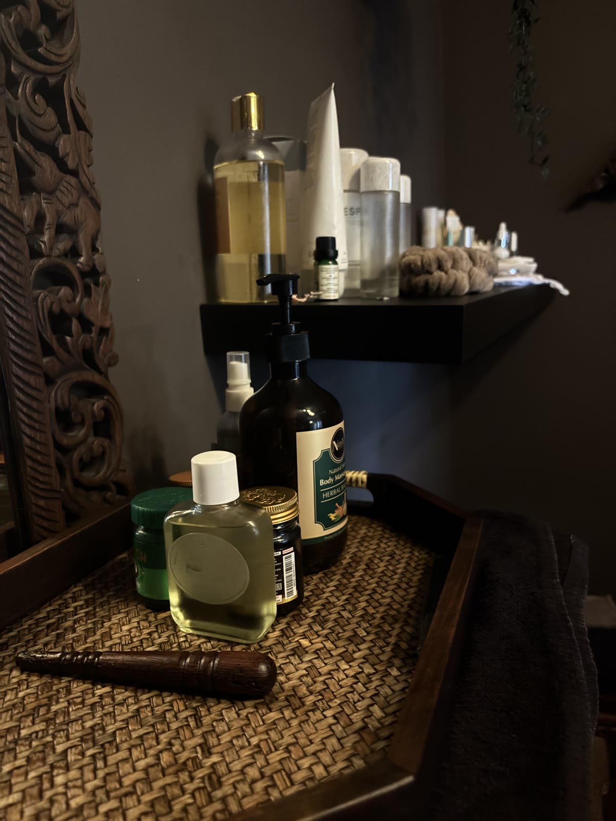 Warmed massage oils, herbal balms and traditional Thai massage tools arranged on a woven tray